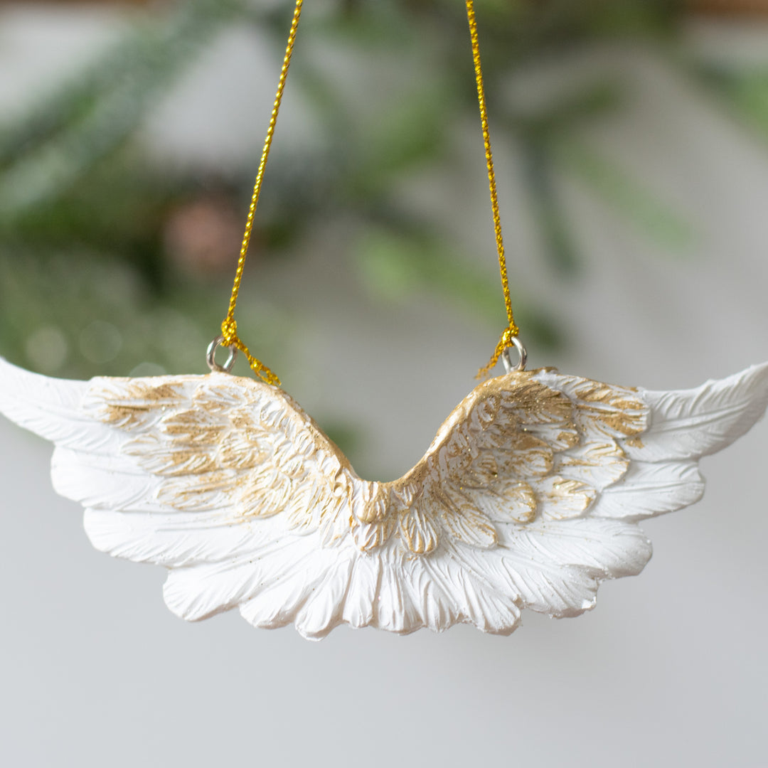 A close-up of a garland with gold bells and red ribbon with a piece of paper below it with the text "Sound Of An Angel Garland" resting on a marble surface