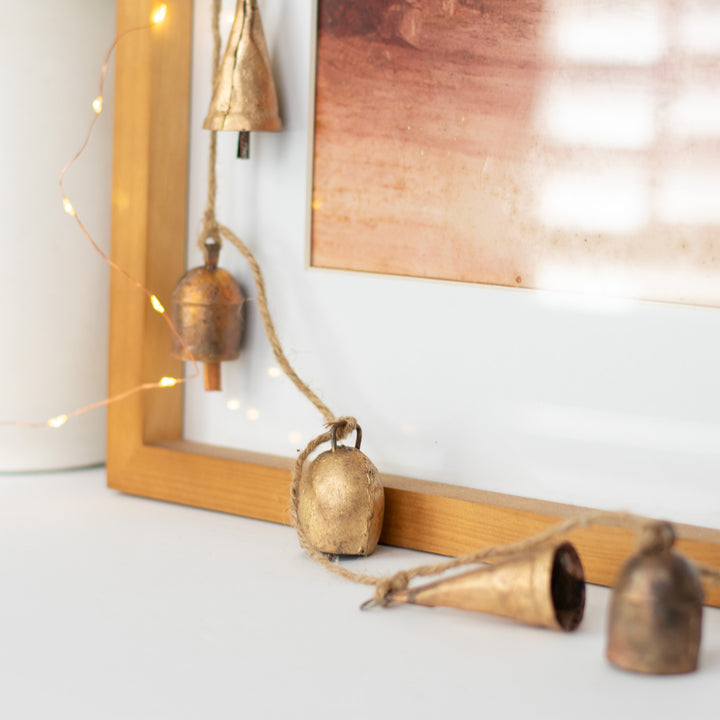 A close-up of a garland with gold bells next to a picture frame