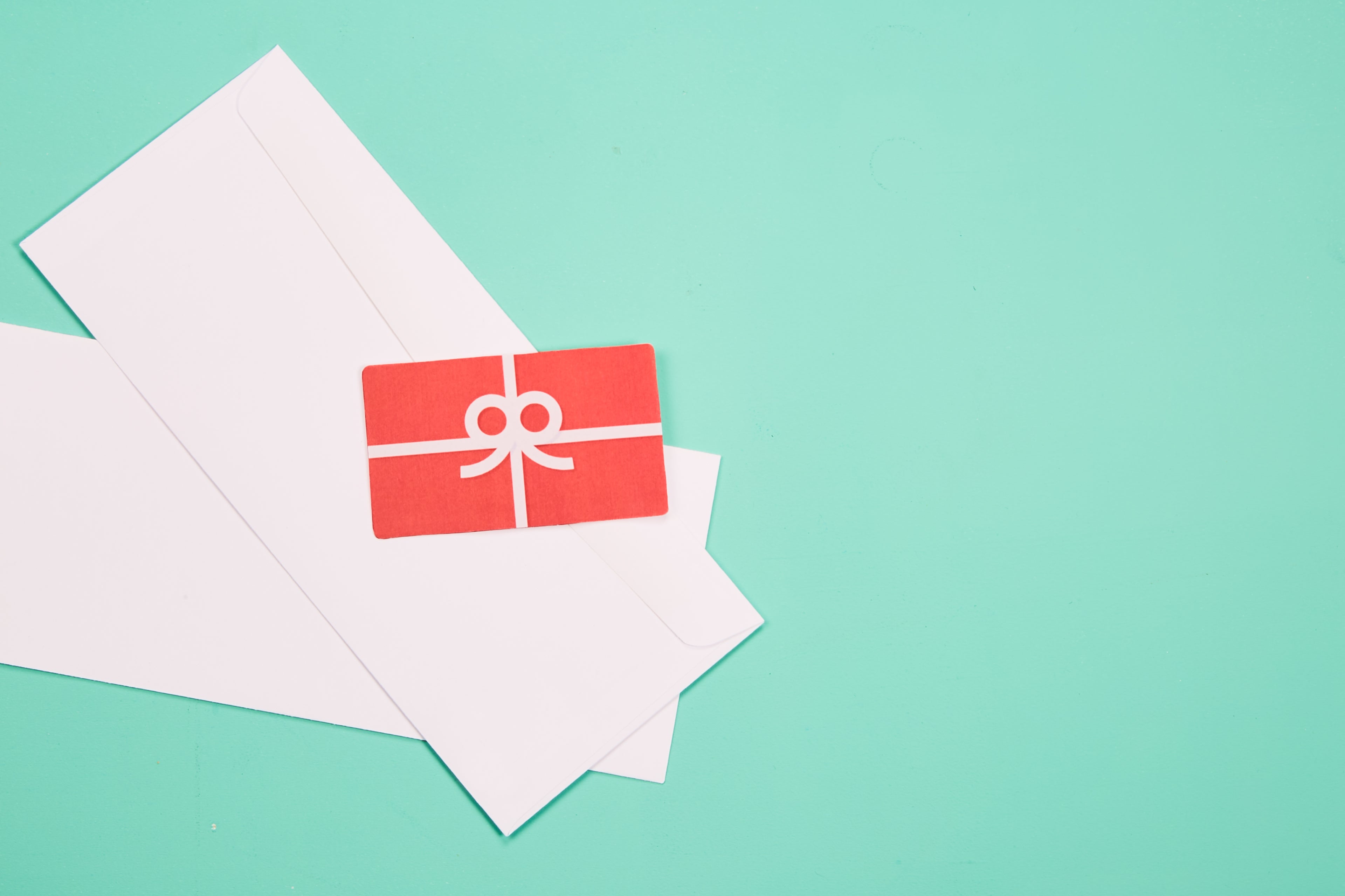 graphic of a bright green background with two white envelopes + a red card with a white bow sitting in the left corner