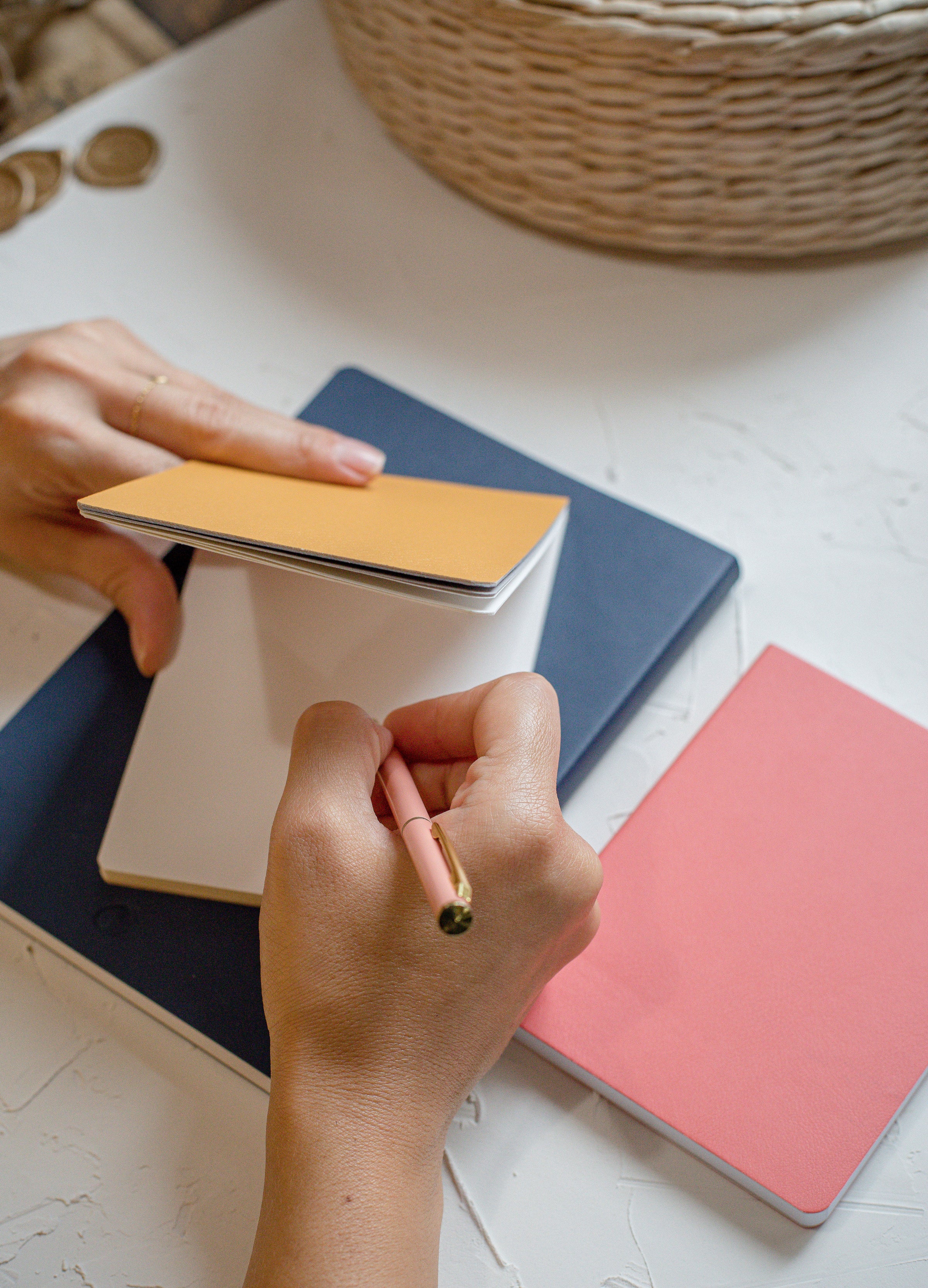 photo of hands writing in a small yellow journal