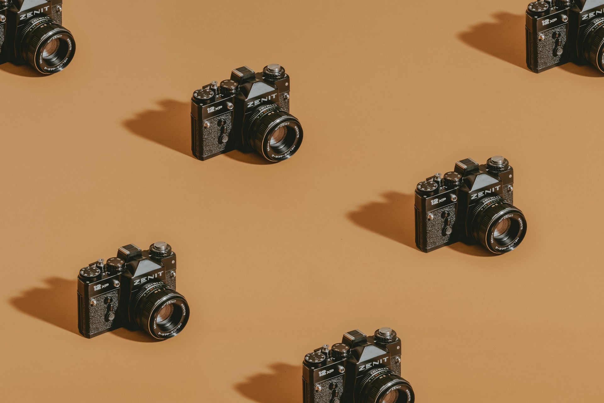 stock photo of several black Zenit cameras spaced out on a orange background