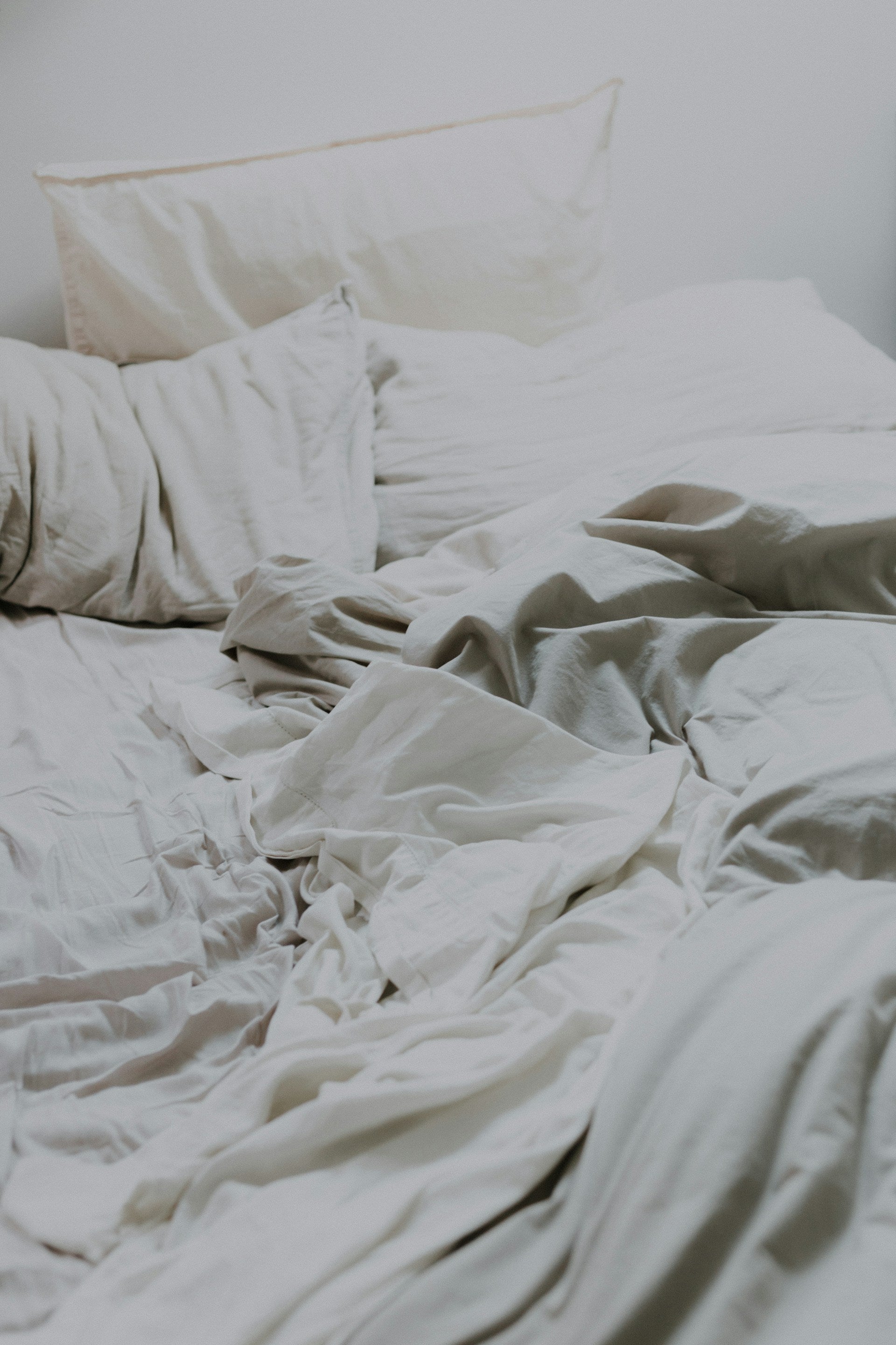 photo of off white bed pillows and sheets that are disheveled