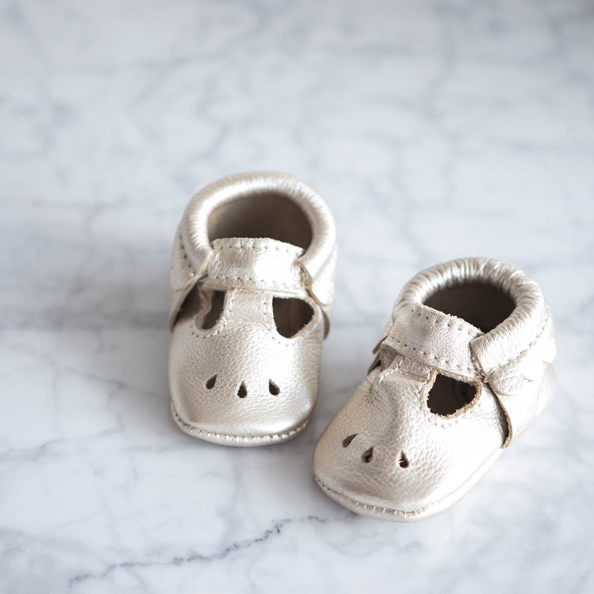 photo of baby silver baby shoes sitting on a marble surface